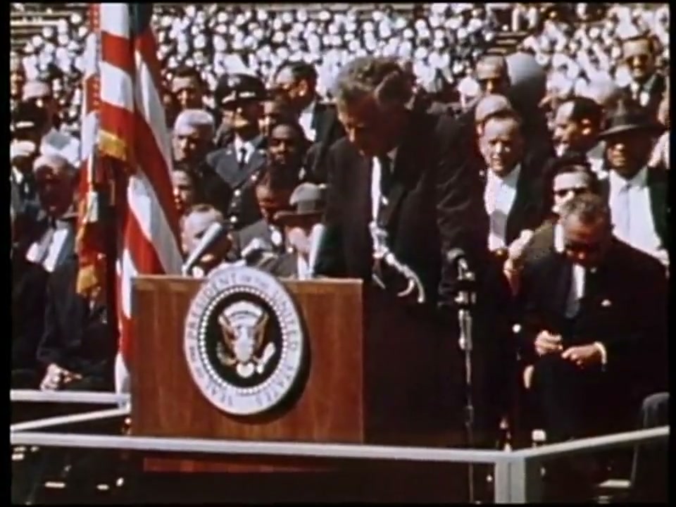 President John F. Kennedy speaking at Rice University beside an American flag