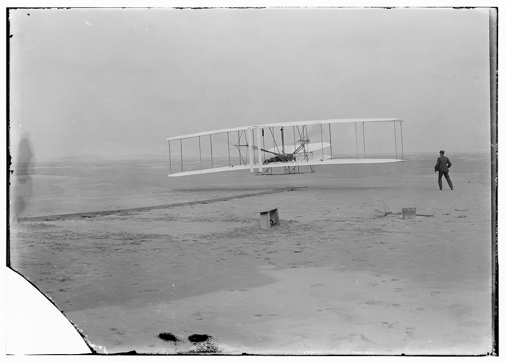 The Wright Flyer airborne on December 17, 1903, with Orville at the controls and Wilbur running alongside.